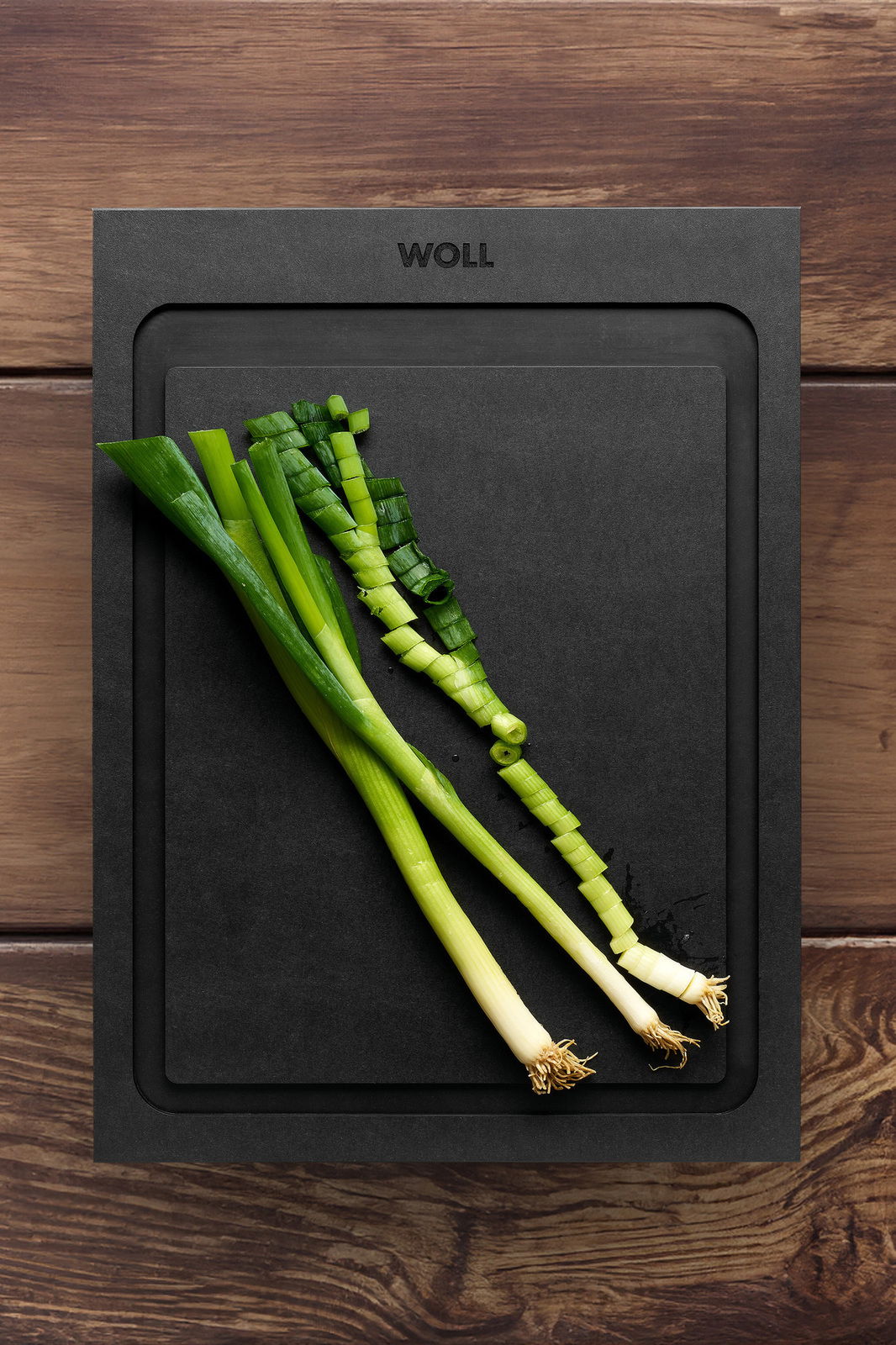 Schwarzes Schneidebrett mit geschnittenen Frühlingszwiebeln, Draufsicht