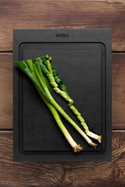 Schwarzes Schneidebrett mit geschnittenen Frühlingszwiebeln, Draufsicht