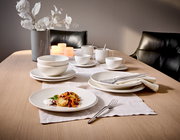 Elegantes 12-teiliges Dinner-Set auf einem gedeckten Tisch, mit einer modernen Perspektive von der Seite fotografiert.