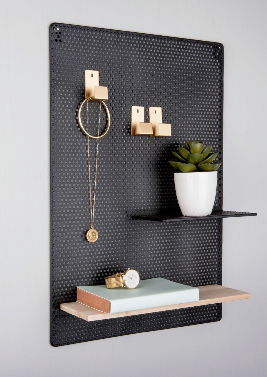 Schwarzes perforiertes Memoboard mit goldenen Haken, einer weißen Pflanzenschale und zwei Regalböden, seitliche Perspektive.