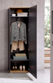 Geöffneter Hochschrank in moderner Umgebung, gefüllt mit Kleidung, Schuhen und Aufbewahrungsboxen, frontal betrachtet.