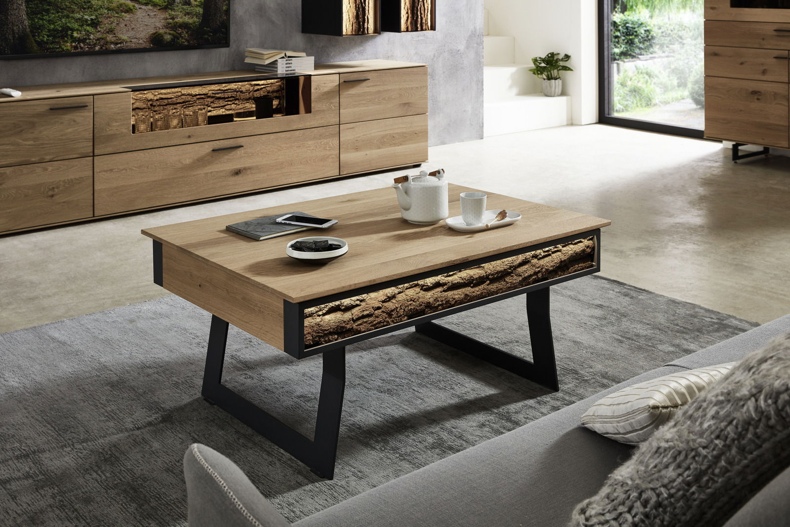 Moderner Couchtisch aus Holz mit schwarzem Metallgestell, dekoriert mit Teeservice und Büchern, in einem stilvollen Wohnzimmer aus seitlicher Perspektive.