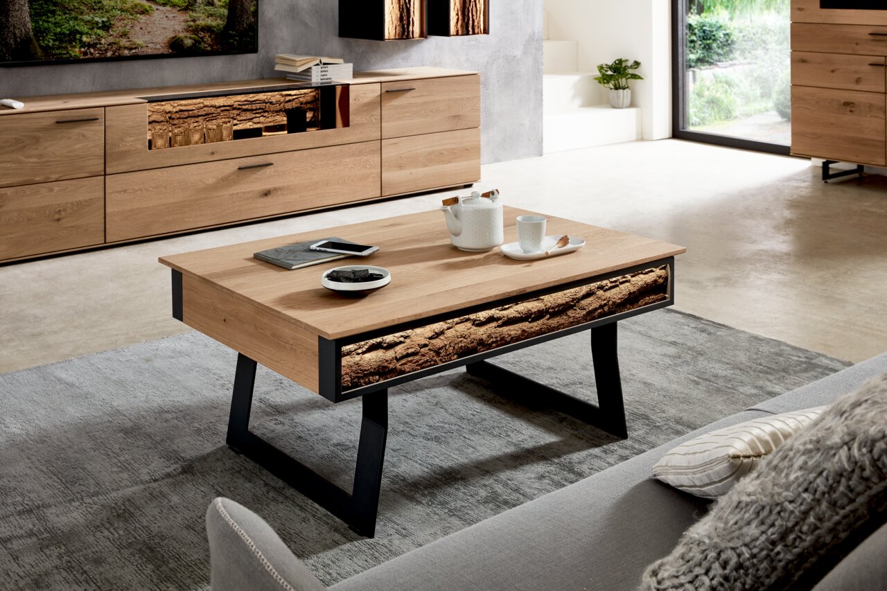 Moderner Couchtisch aus Holz mit schwarzem Metallgestell, dekoriert mit Teeservice und Büchern, in einem stilvollen Wohnzimmer aus seitlicher Perspektive.