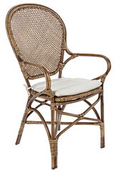 Rattan-Stuhl mit Armlehnen und weißem Sitzkissen, seitliche Perspektive