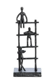 Metallskulptur mit drei stilisierten Figuren auf einem gestuften Gerüst, frontal betrachtet.