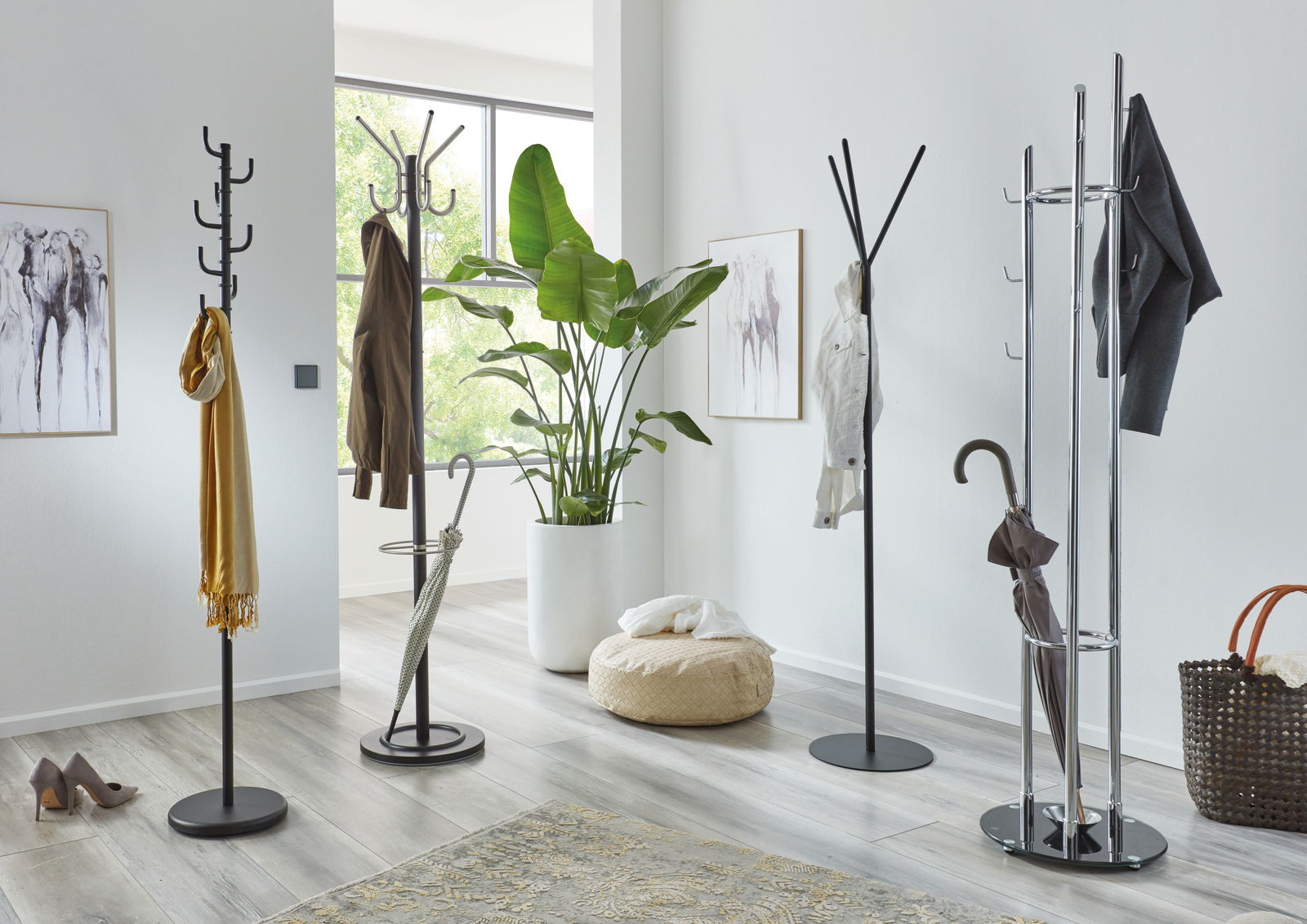 Mehrere Garderobenständer in einem modernen, hellen Raum mit Pflanzen und Dekorationen, aus seitlicher Perspektive fotografiert.