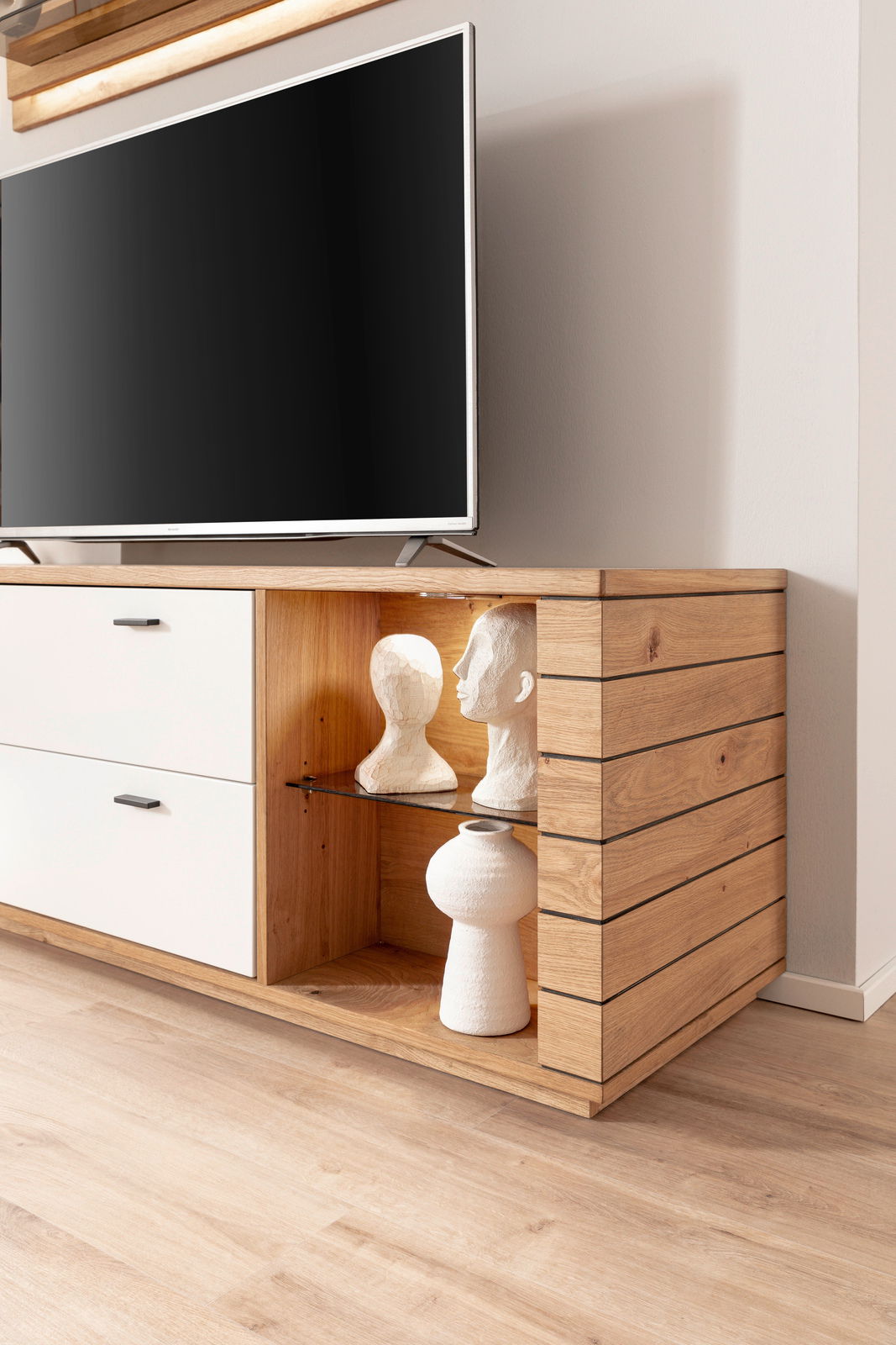 Novel LED-Flat-Powerspot MANITOBA Holz-Sideboard mit weißen Schubladen und dekorativen Skulpturen, seitliche Perspektive