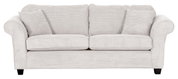 Beige driezitsbank met geribbelde stoffen bekleding, twee grote rugkussens en twee kleine sierkussens, gezien van voren.
