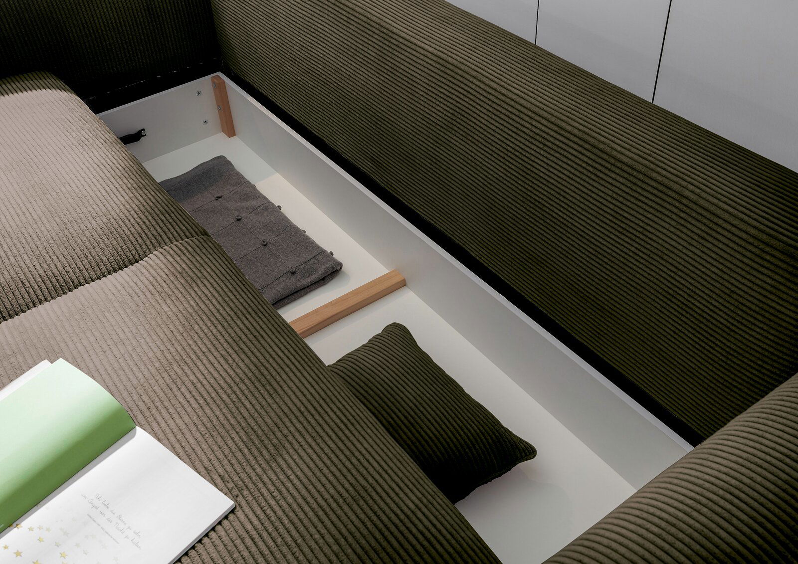 Funktionssofa mit Stauraum, Ansicht von oben, zeigt geöffnete Aufbewahrung mit Kissen und Decke.