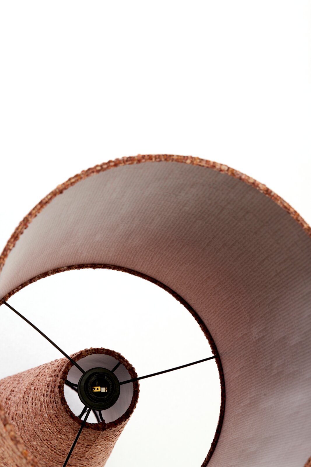 Detailaanzicht van onderaf van een roze stoffen lampenkap met zichtbare fitting en zwart metalen frame