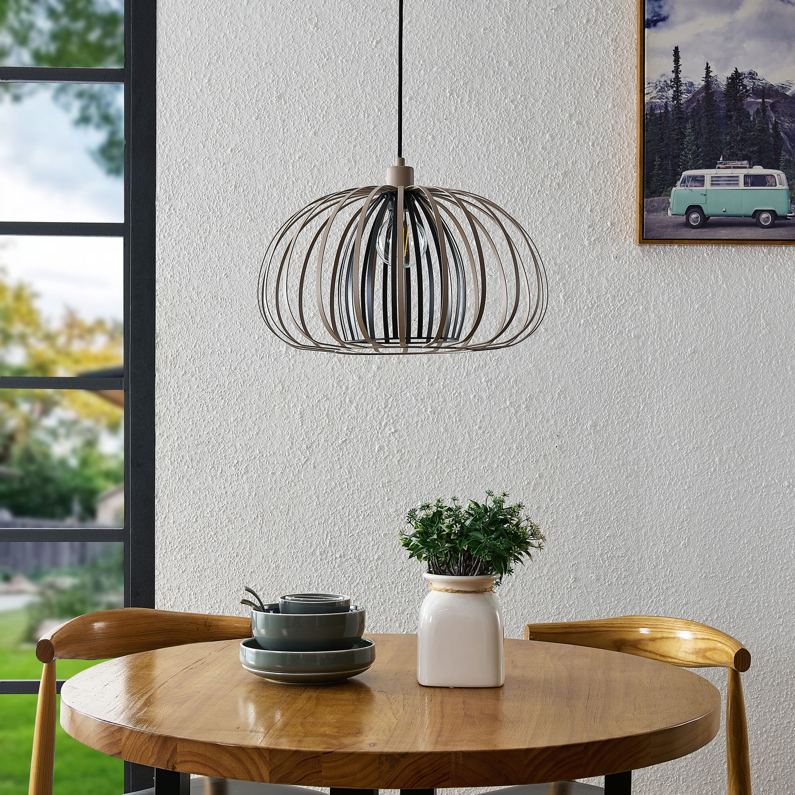 Moderne Hängeleuchte mit Metallrahmen über einem runden Holztisch, seitliche Perspektive.