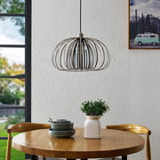 Moderne Hängeleuchte mit Metallrahmen über einem runden Holztisch, seitliche Perspektive.