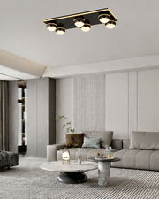 Moderne LED-Deckenleuchte mit sechs runden Leuchtkörpern in einem stilvollen Wohnzimmer, Perspektive von unten.