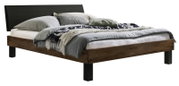 Modern tweepersoonsbed met houten frame in donkere eikenlook, zwart gestoffeerd hoofdeinde en zwarte poten, met grijs beddengoed en kussens, schuin van linksvoor gefotografeerd.