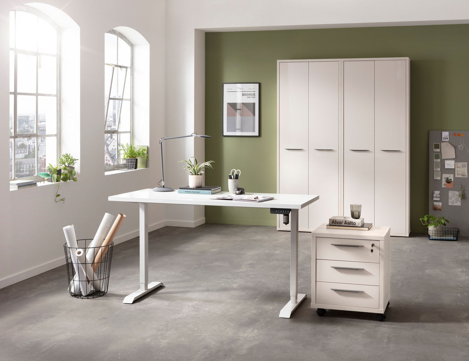 Moderner, elektrisch höhenverstellbarer Schreibtisch in einem hellen Büro mit grüner Akzentwand, seitlicher Perspektive.