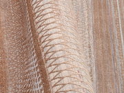 Nahaufnahme eines Designer Teppichs mit geometrischem Muster in Beige- und Brauntönen, aus seitlicher Perspektive aufgenommen.