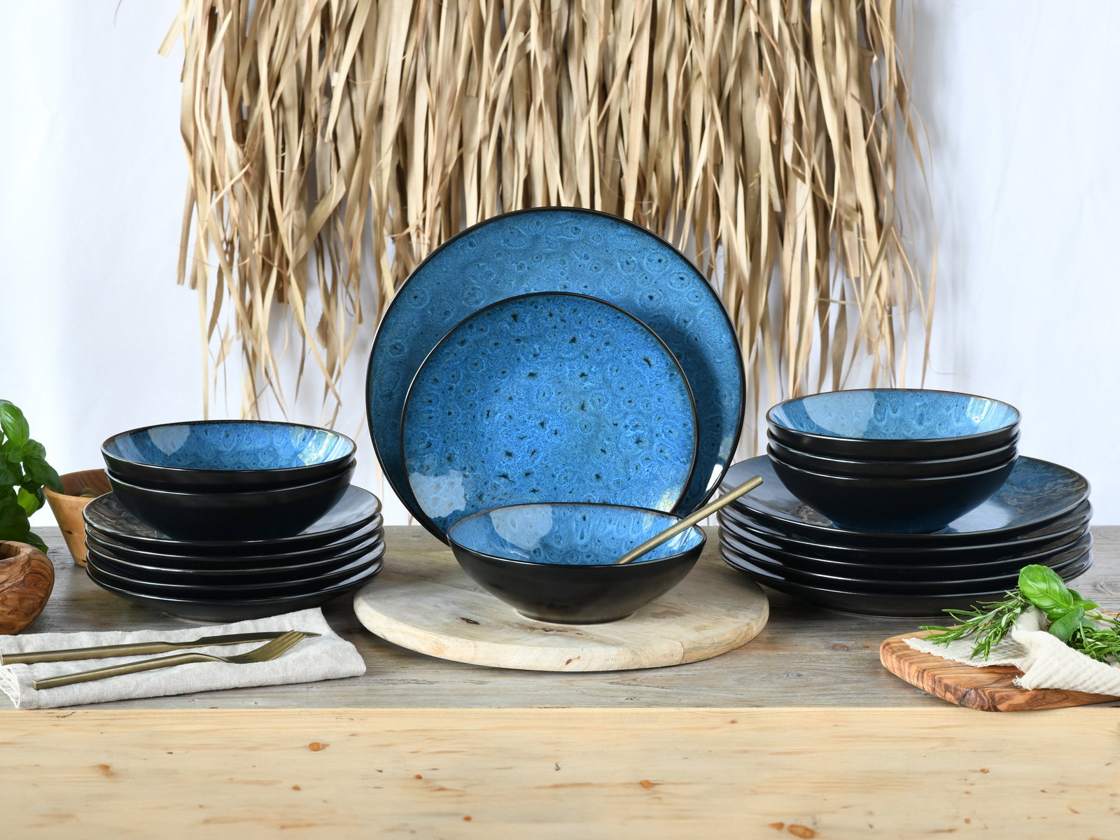 Tellerset 18-tlg mit blauer Innenseite und schwarzer Außenseite, frontal präsentiert auf einem Holztisch mit dekorativen Elementen.