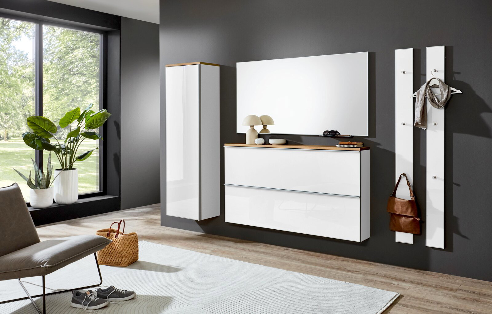 Moderne weiße Hochglanz-Garderobe mit wandhängendem Schuhschrank, Spiegel, Hochschrank und zwei Garderobenpaneelen an dunkelgrauer Wand, gezeigt in frontaler Perspektive mit leichter Seitenansicht.