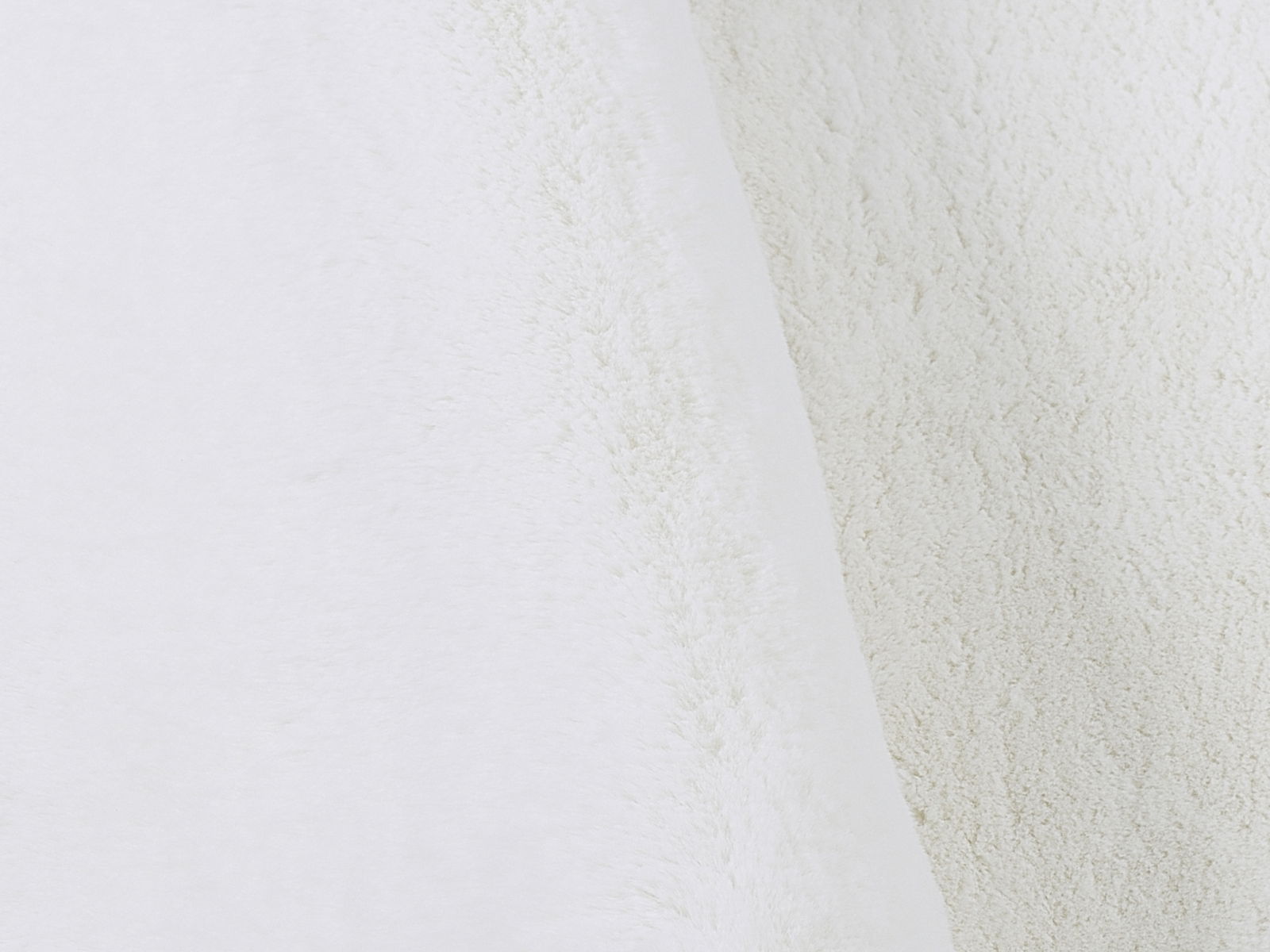 Nahaufnahme eines weißen, weichen Fellteppichs mit flauschiger Textur.