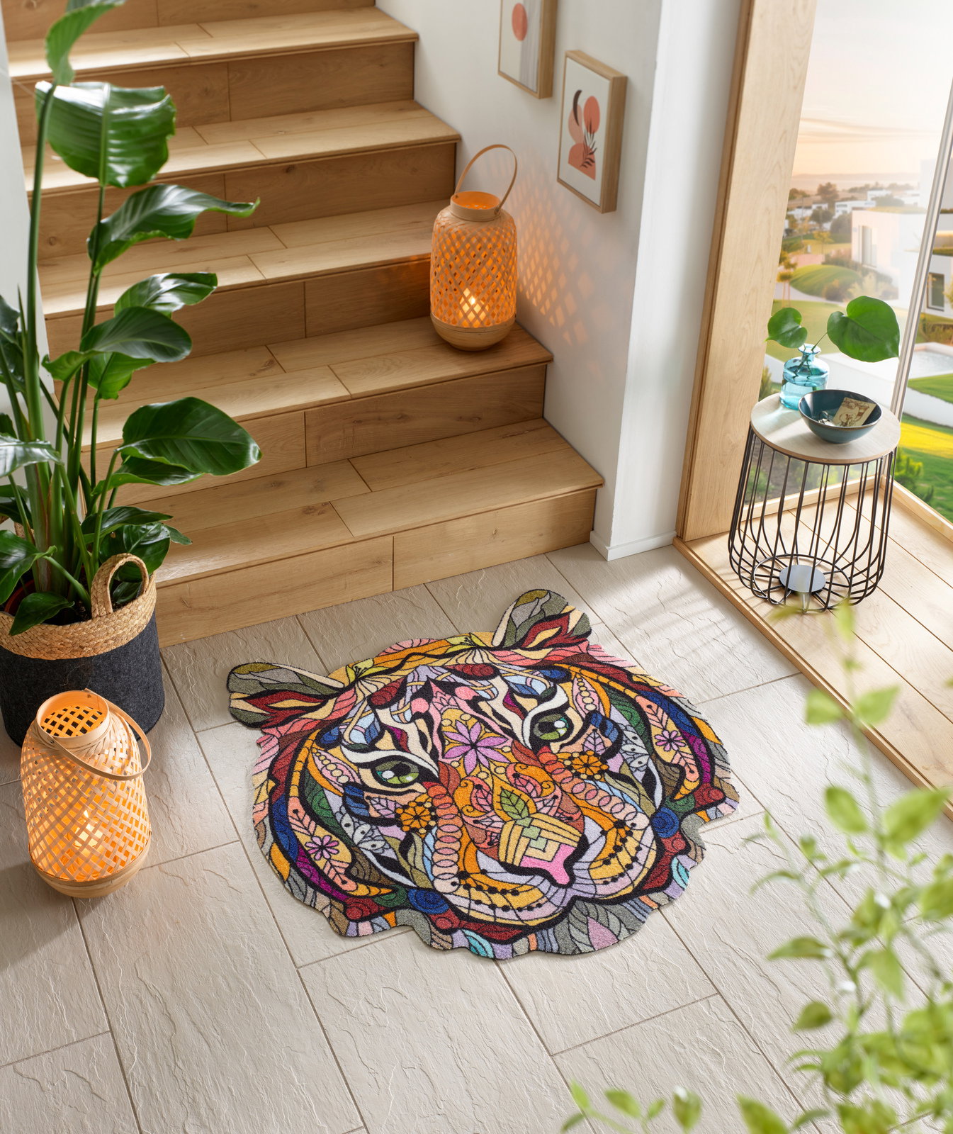 Bunte Fußmatte in Form eines Tigerkopfes mit abstraktem, geometrischem Design, platziert auf einem hellen Fliesenboden neben einer Holztreppe. Perspektive von oben.