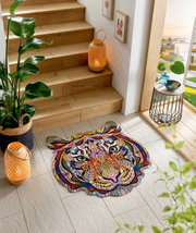 Bunte Fußmatte in Form eines Tigerkopfes mit abstraktem, geometrischem Design, platziert auf einem hellen Fliesenboden neben einer Holztreppe. Perspektive von oben.