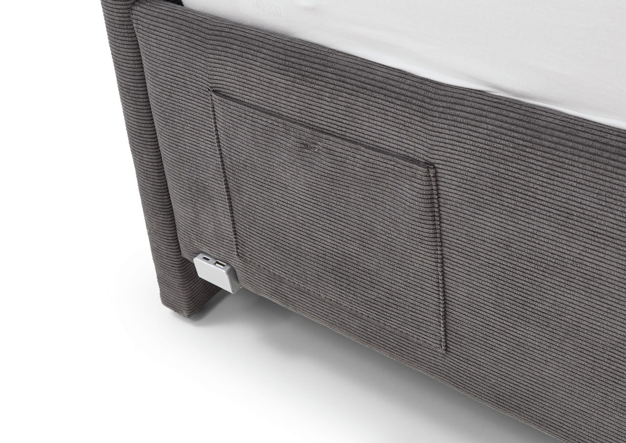 Nahaufnahme der Seite einer grauen Polsterliege mit strukturiertem Stoff und Metallfuß.