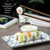 Sushi-Set mit blauen Blumenmuster, bestehend aus einem rechteckigen Teller mit Sushi-Rollen und Holzstäbchen, aus der Seitenperspektive fotografiert.