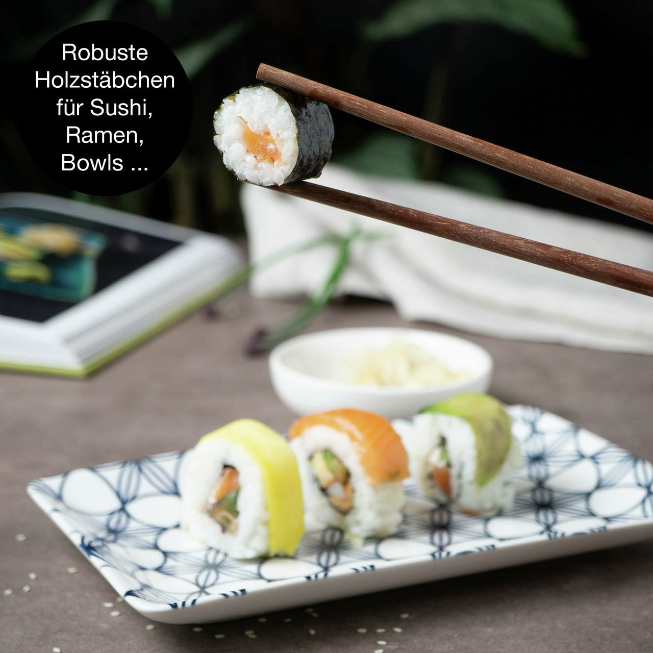 Sushi-Set mit blauen Blumenmuster, bestehend aus einem rechteckigen Teller mit Sushi-Rollen und Holzstäbchen, aus der Seitenperspektive fotografiert.
