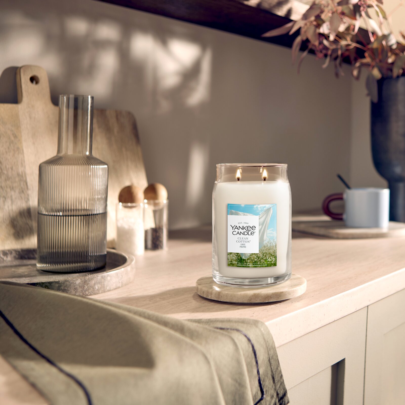 Brennende Yankee Candle Clean Cotton Duftkerze im großen Glas mit zwei Dochten, frontal aus leicht erhöhter Perspektive auf einem hellen Küchentisch inszeniert