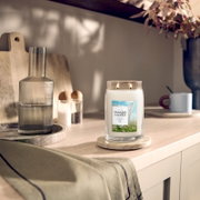 Brennende Yankee Candle Clean Cotton Duftkerze im großen Glas mit zwei Dochten, frontal aus leicht erhöhter Perspektive auf einem hellen Küchentisch inszeniert