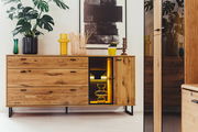 Holz-Sideboard mit Schubladen und Glastür, dekoriert mit Pflanzen und Vasen, aus frontaler Perspektive.