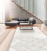 Moderne Longchair-Kombination in einem stilvollen Wohnzimmer, seitliche Perspektive. Dunkles Ledersofa mit gelbem und grauem Kissen, Couchtisch aus Metall und Holz, helle Holzböden und eine elegante Treppe im Hintergrund.