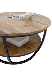 Runder Couchtisch aus Holz mit schwarzem Metallrahmen, von schräg oben fotografiert. Auf der Tischplatte liegen Kopfhörer und Fotos, darunter befindet sich ein Regal mit einer Box.