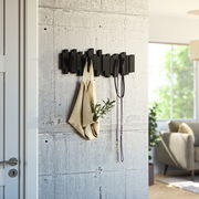 Moderne schwarze Wandgarderobe mit geometrischem Design, an der eine Tasche und ein Seil hängen. Perspektive von der Seite.