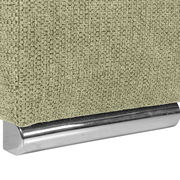 Nahaufnahme einer grünen, texturierten Stoffoberfläche mit einem glänzenden, metallischen Sockel. Perspektive von der Seite.