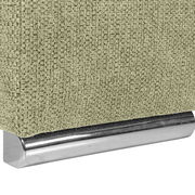 Nahaufnahme einer grünen, texturierten Stoffoberfläche mit einem glänzenden, metallischen Sockel. Perspektive von der Seite.