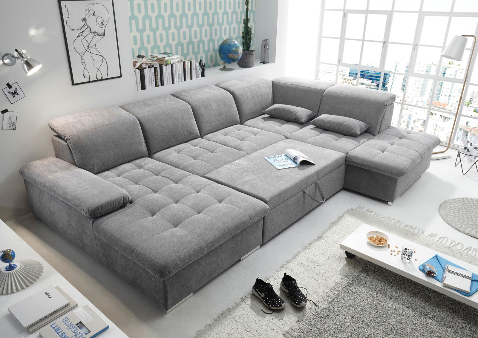 Graue Wohnlandschaft WAYNE in U-Form mit großzügiger Sitzfläche und verstellbaren Kopfstützen, abgebildet aus einer leicht erhöhten Perspektive in einem modernen Wohnzimmer.