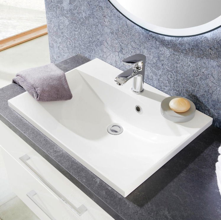 Moderne Waschbecken-Kombination mit Armatur, Seifenschale und Handtuch, aus der Vogelperspektive fotografiert.