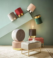 Verschiedene Hocker und eine Hockerbank in einem modernen Raum, mit goldenen Akzenten und weichen Stoffen, aus einer seitlichen Perspektive fotografiert.