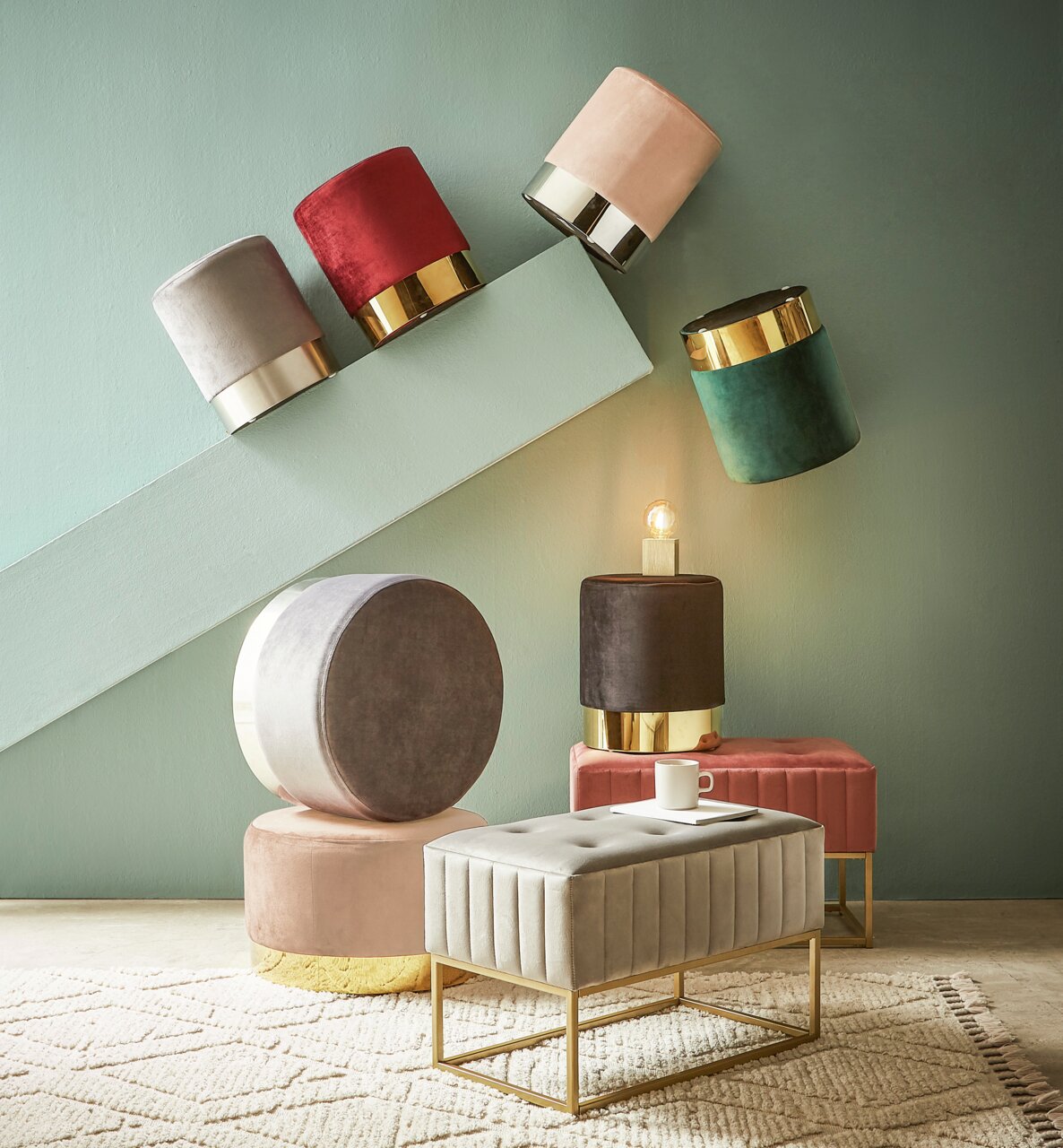 Verschiedene Hocker und eine Hockerbank in einem modernen Raum, mit goldenen Akzenten und weichen Stoffen, aus einer seitlichen Perspektive fotografiert.