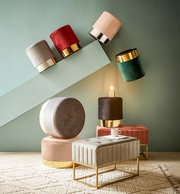 Verschiedene Hocker und eine Hockerbank in einem modernen Raum, mit goldenen Akzenten und weichen Stoffen, aus einer seitlichen Perspektive fotografiert.