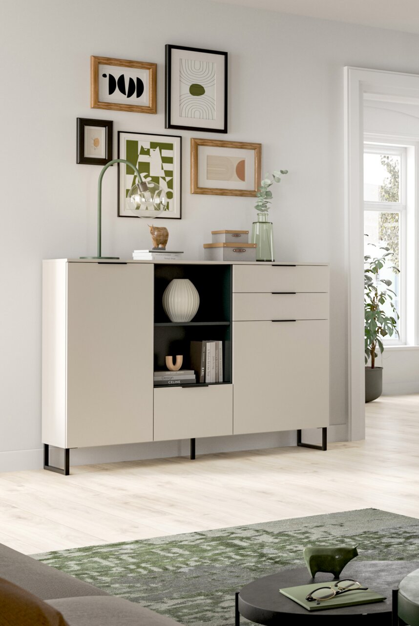 Modernes Sideboard in Cremeweiß mit schwarzen Metallfüßen, mittigem offenem Regal und drei Schubladen rechts, in einem hellen Wohnzimmer dekoriert Perspektive: frontale Ansicht leicht von links