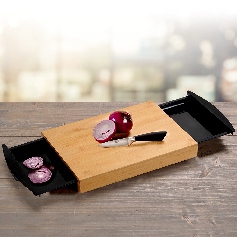 Kesper Schneidebrett mit Auffangschale Schneidebrett aus Holz mit zwei ausziehbaren Auffangschalen, darauf eine geschnittene Zwiebel und ein Messer, Perspektive von oben.