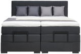 Frontale Ansicht eines modernen Boxspringbetts mit grauem Kopfteil und vier passenden Kissen.