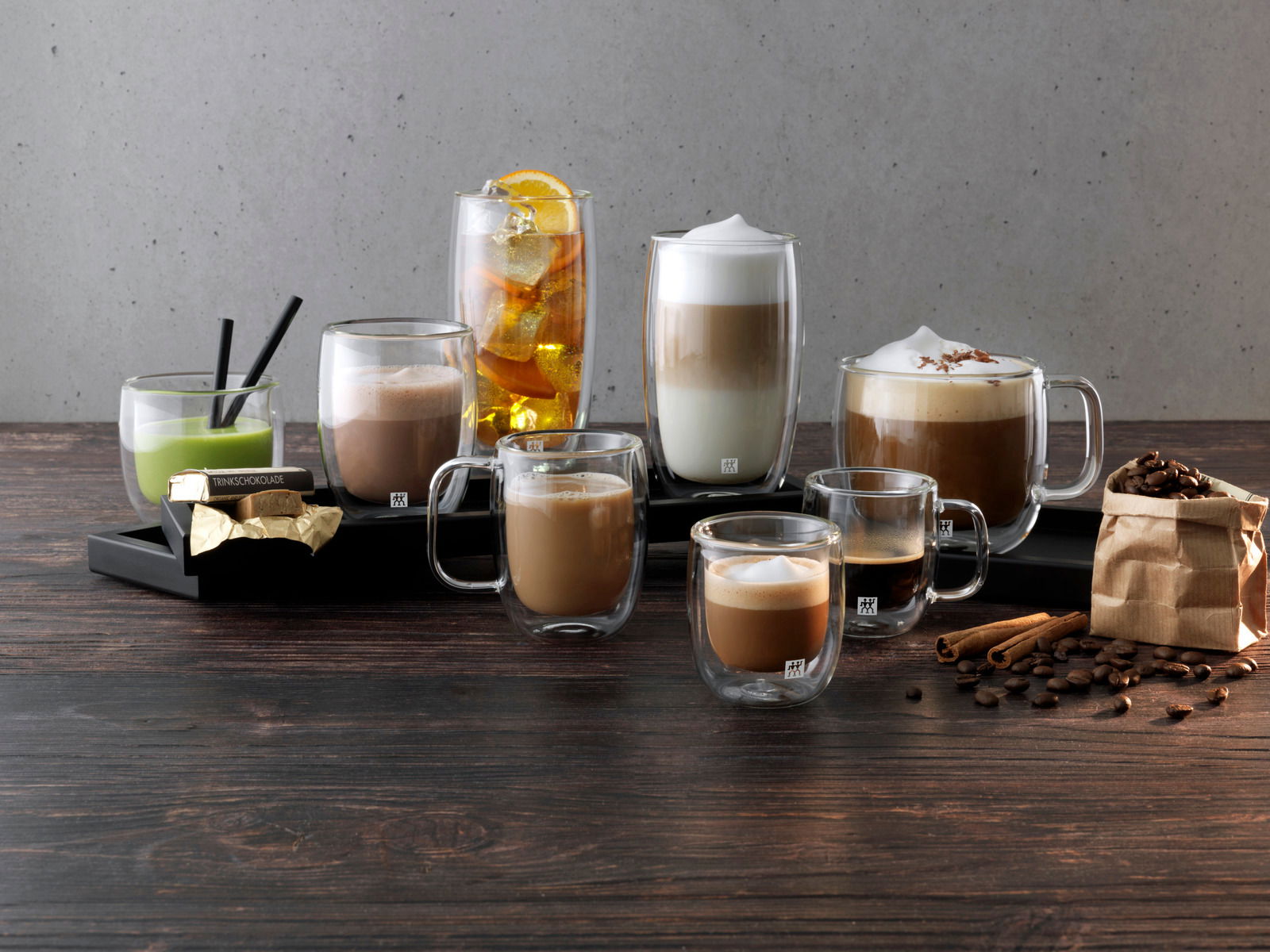 ZWILLING Latte Macchiato Glasset 2-tlg. SORRENTO Verschiedene Getränke in doppelwandigen Gläsern, darunter Latte Macchiato, auf einem Tisch mit Kaffeebohnen und Zimtstangen, seitliche Perspektive.