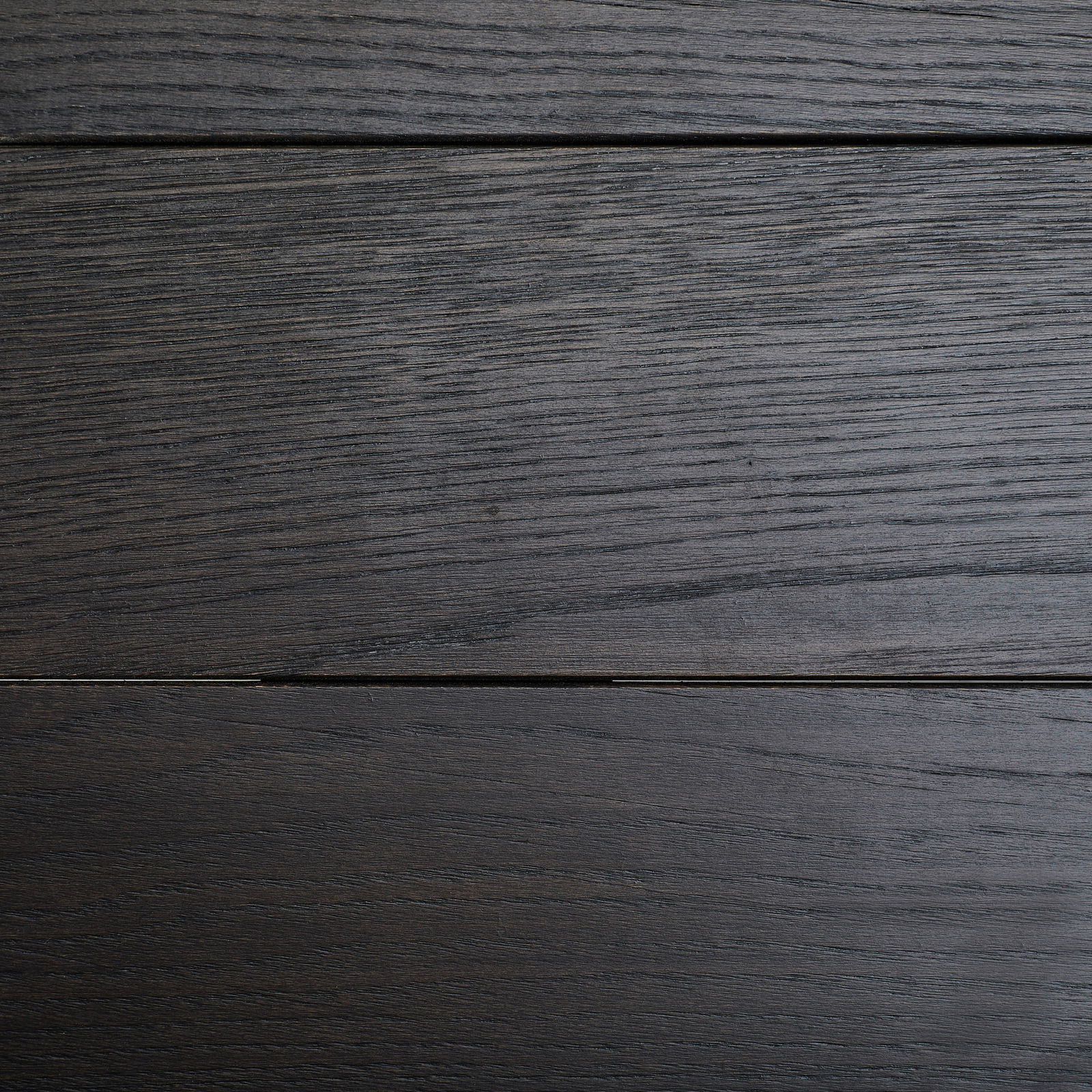 Draufsicht auf eine dunkle Holzoberfläche eines Esstisches mit sichtbarer Maserung.