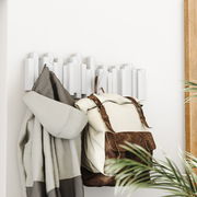 Moderne Wandgarderobe mit geometrischem Design, von der Seite fotografiert, mit einem Mantel und einem Rucksack behängt.