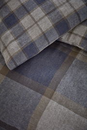 Nahaufnahme von kariertem Bettwäsche-Set in Blau- und Brauntönen, perspektivisch von oben fotografiert.