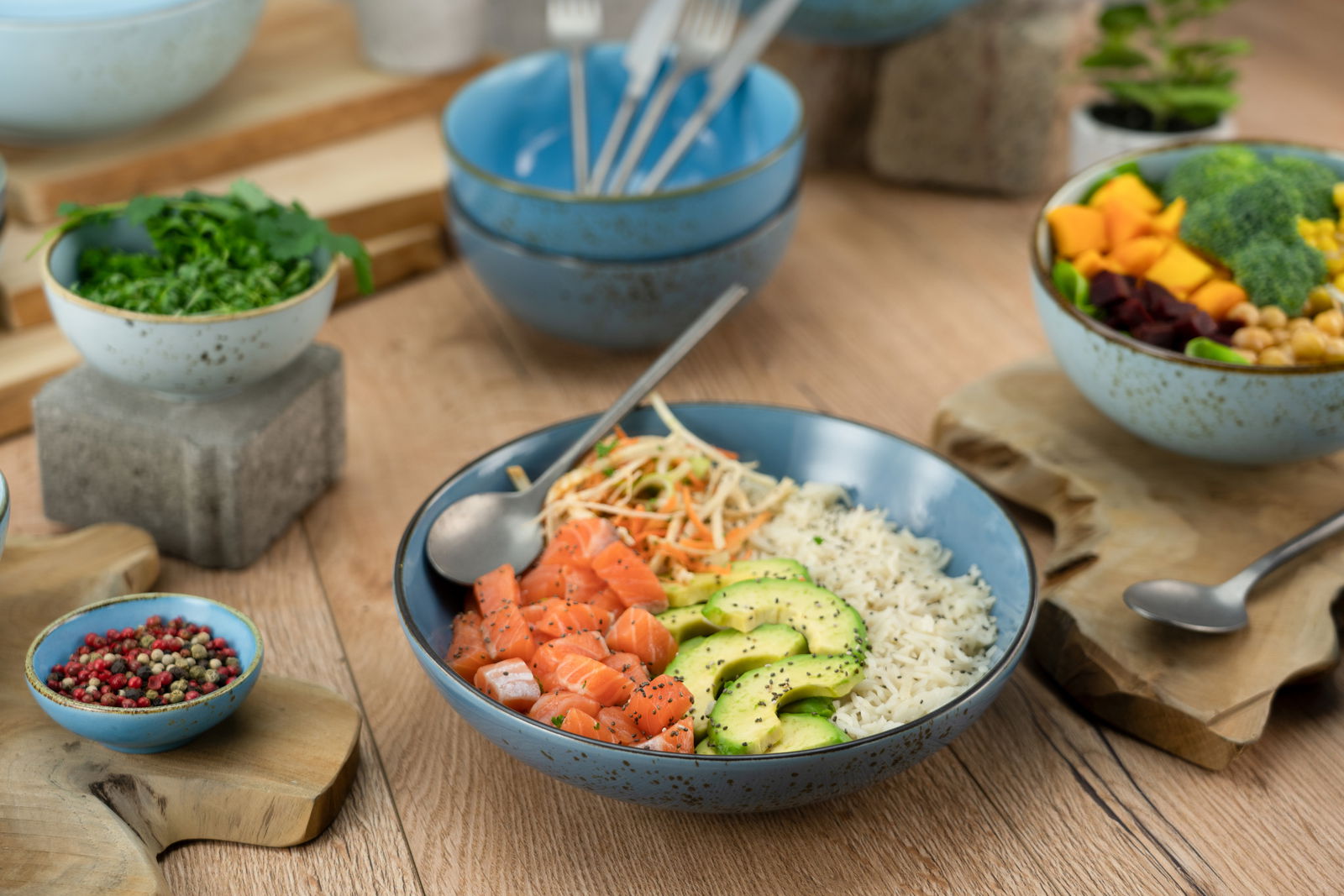 Creatable Poke Bowl 4-tlg NATURE COLLECTION Poke Bowl Set aus vier Teilen in blauer Keramik, gefüllt mit frischen Zutaten wie Lachs, Avocado und Reis, aus der Vogelperspektive fotografiert.
