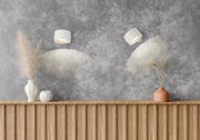 Zwei weiße, zylindrische Wandspots an grauer Strukturwand, die warmes Licht nach unten werfen; Frontansicht der Wand mit leicht schräger Perspektive auf die rechte Leuchte über Holzsideboard mit Deko-Vasen.